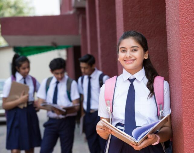 Young girl in school uniform smiling with textbook